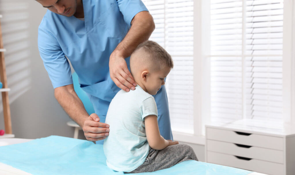 Orthopedist examining child's back in clinic. Scoliosis treatment